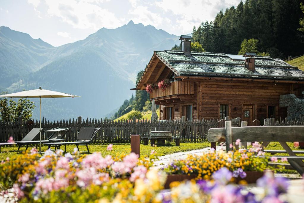 a log cabin with a table and chairs and flowers at New Chalet Brunegg Weissenbach in Rio Bianco