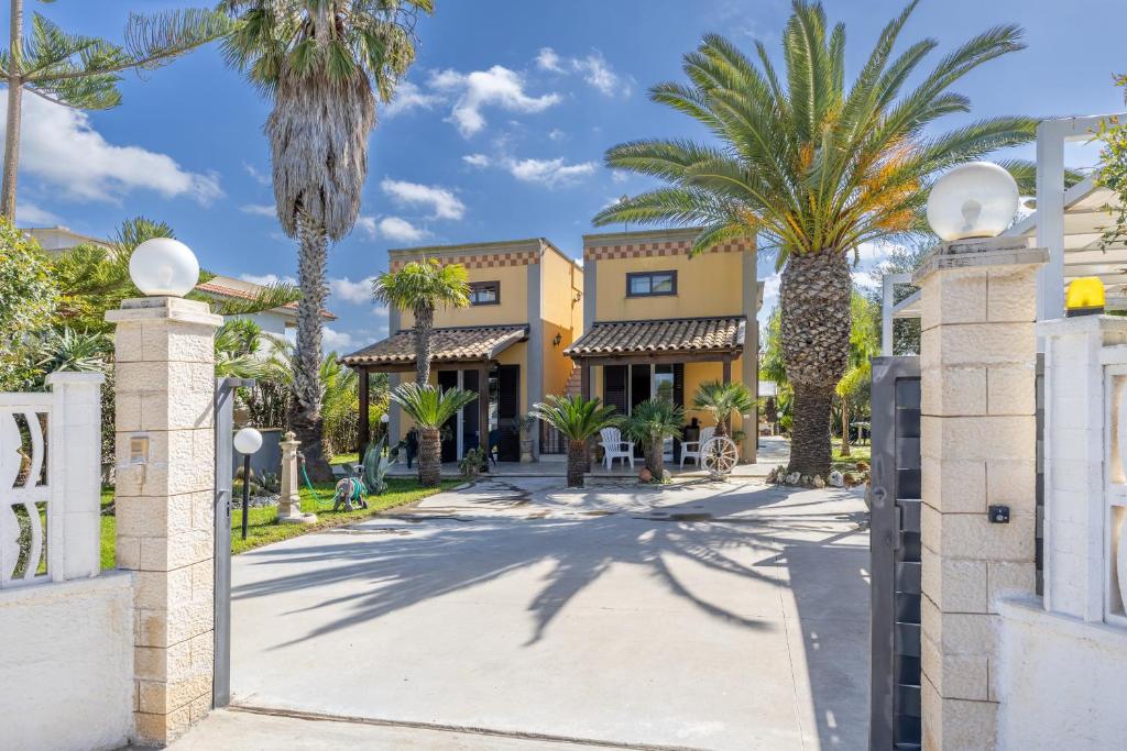 a street in front of a building with palm trees at Villa Forino Ragusa in Santa Maria del Focallo