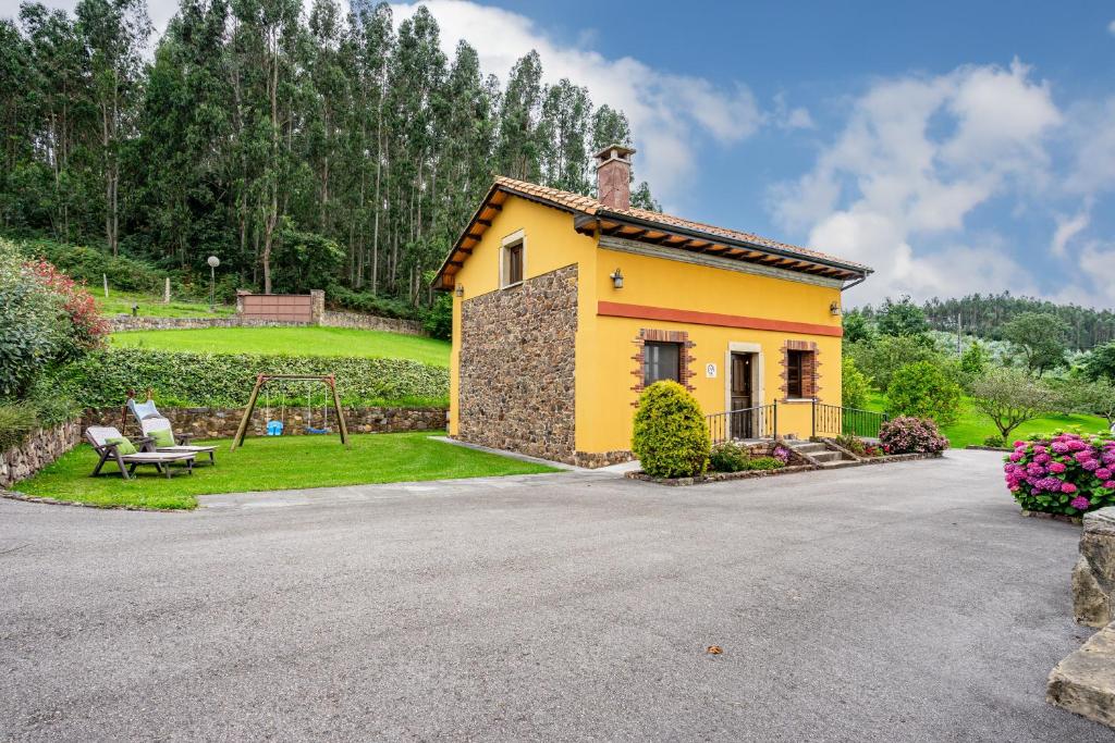 a small yellow house with a swing in a yard at Casa Jesusa in Gijón