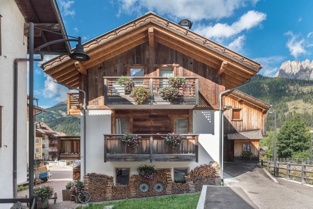 a house with a balcony in the mountains at Appartamento Ciasa in Pozza di Fassa