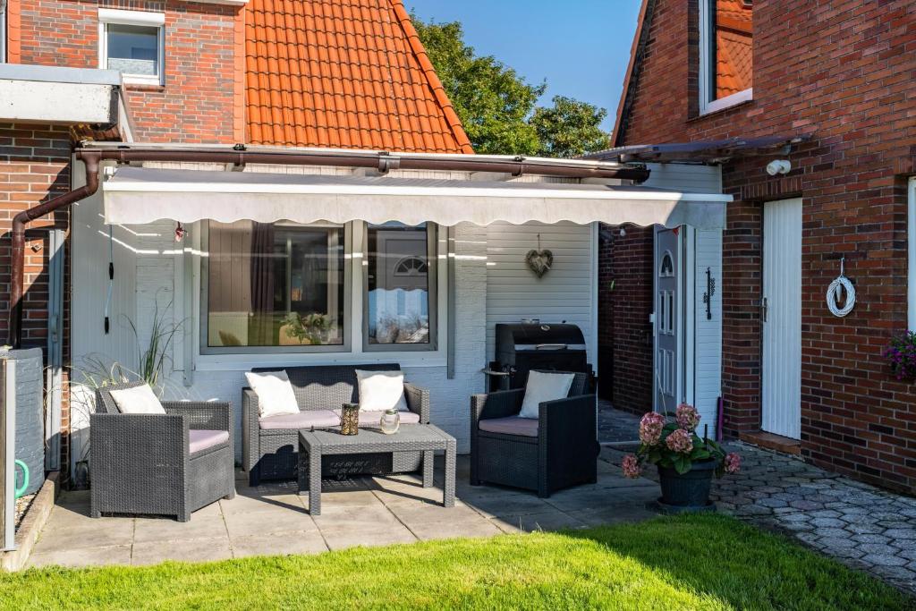 a patio with chairs and an awning on a house at Ferienhaus Ihme in Sande