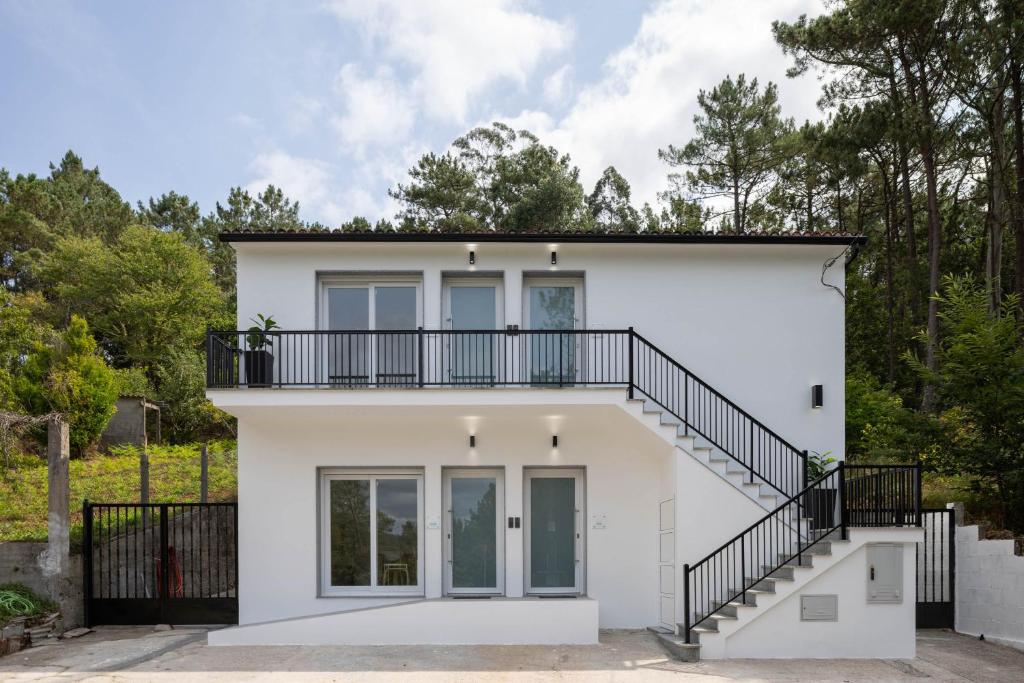 a white house with a balcony and stairs at Aptos Ría San Cosme Aurora in Bendimón