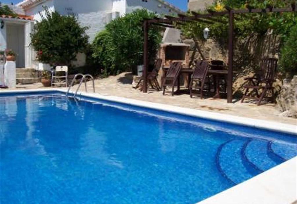 a large blue swimming pool with a table and chairs at Casa Jazmin in Roses