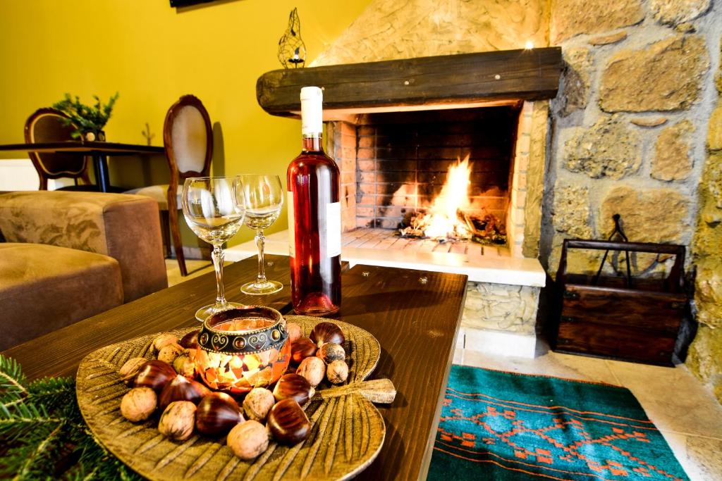 un tavolo con un piatto di bicchieri da cibo e vino e un camino di Korfes Guesthouse a Synikia Mesi Trikalon