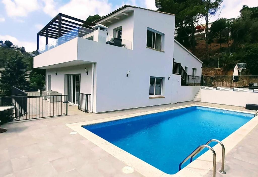 a villa with a swimming pool in front of a house at Casa Nuestra in Begur