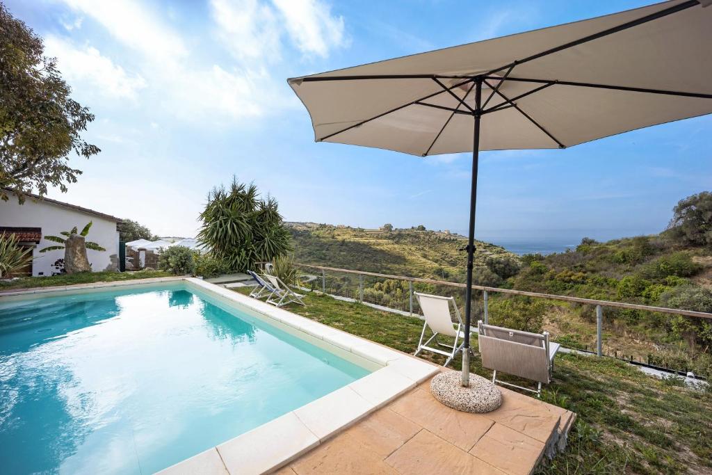 an umbrella and chairs next to a swimming pool at Il Nido in Pompeiana