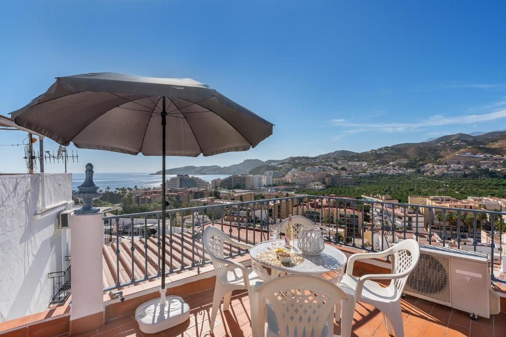 a balcony with a table and chairs and an umbrella at Casa Carmen in Almuñécar
