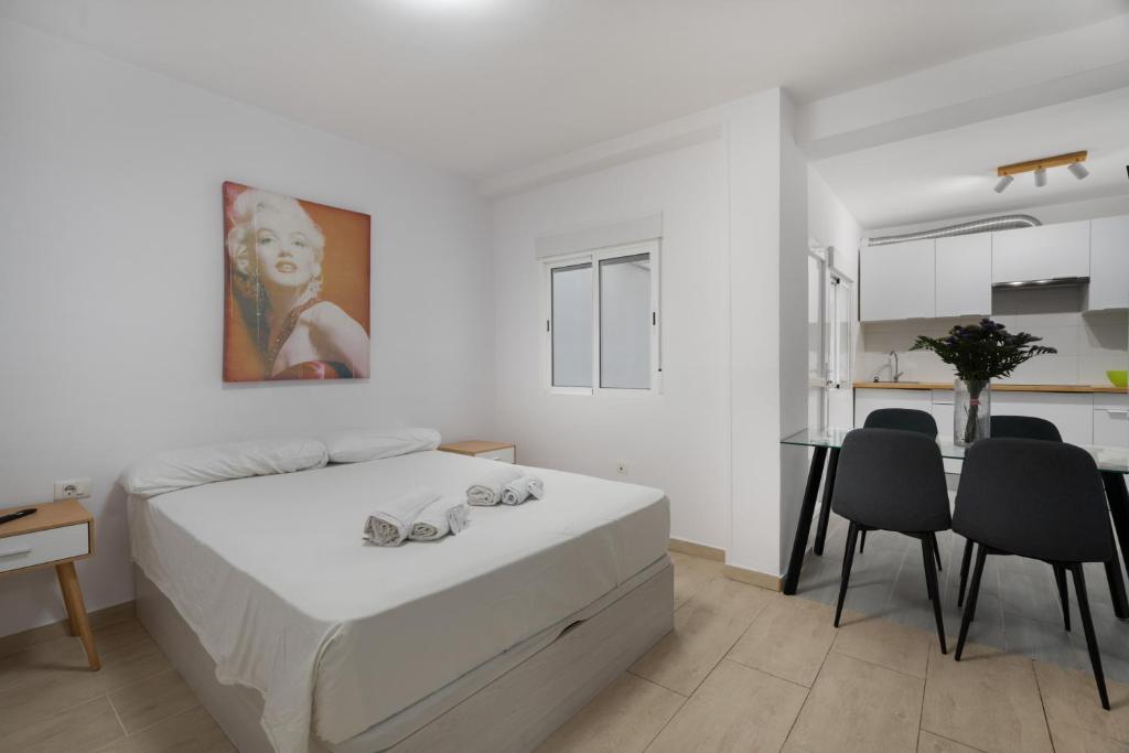 a white bedroom with a bed and a table and chairs at Loft Guanapay 2 in Los Cristianos