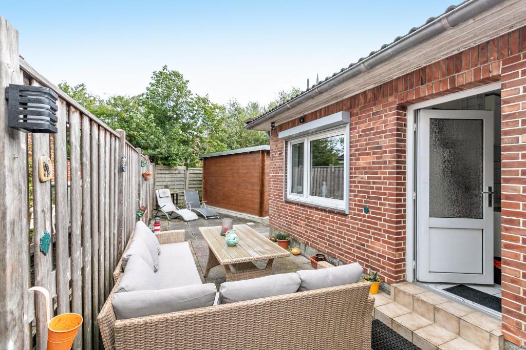 a patio with couches and a table on a brick building at Bungalow vor Sylt in Klanxbüll