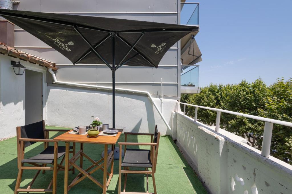 a table and chairs on a balcony with an umbrella at Portblanc Front in Arenys de Mar