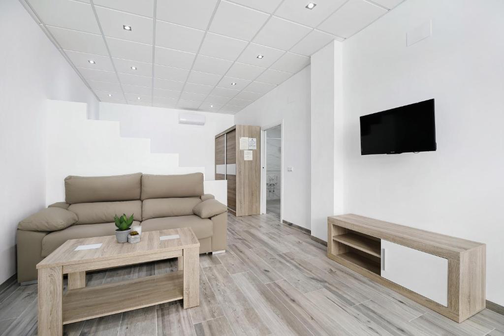 a living room with a couch and a tv on a wall at Apartamento Venus 2 in Conil de la Frontera