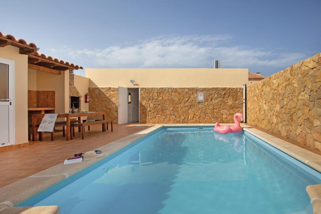 a swimming pool in a villa with a stone wall at Seguidilla Relax in Gran Tarajal