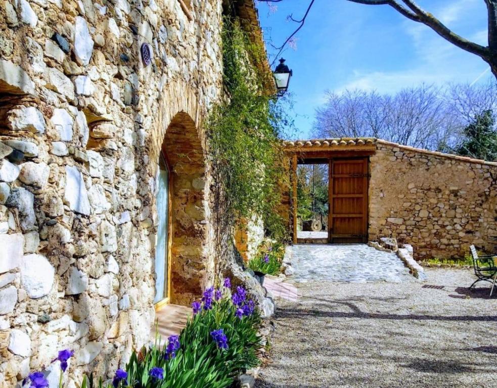 a stone house with a stone wall and purple flowers at Miramar in Montblanc