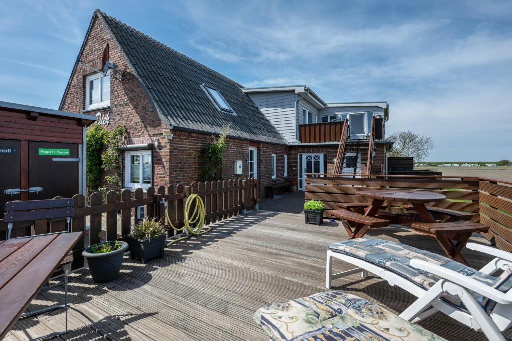 a deck with picnic tables and a house at Huus achtern Diek in Nordstrand