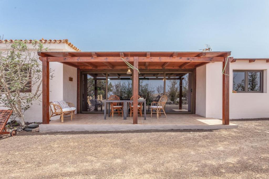a wooden pergola with a table and chairs on a patio at Oasis en Cotillo in Roque