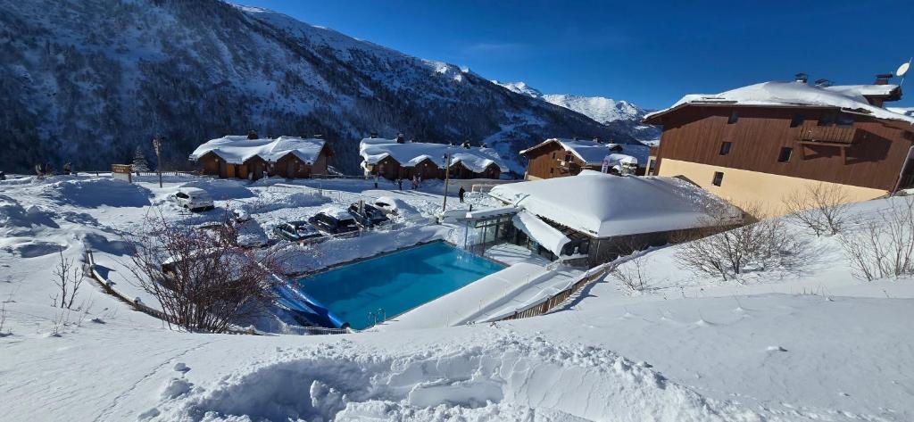 a house covered in snow with a swimming pool at Appartement Valmeinier 1800 in Valmeinier