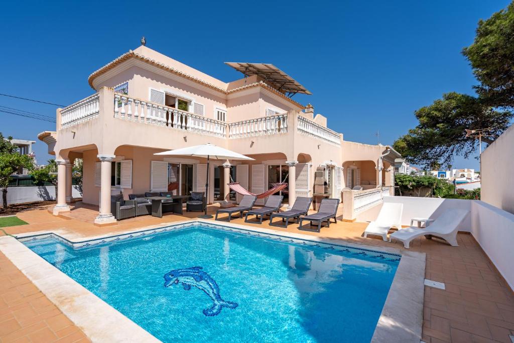 a villa with a swimming pool in front of a house at Poiso da Águia in Carvoeiro
