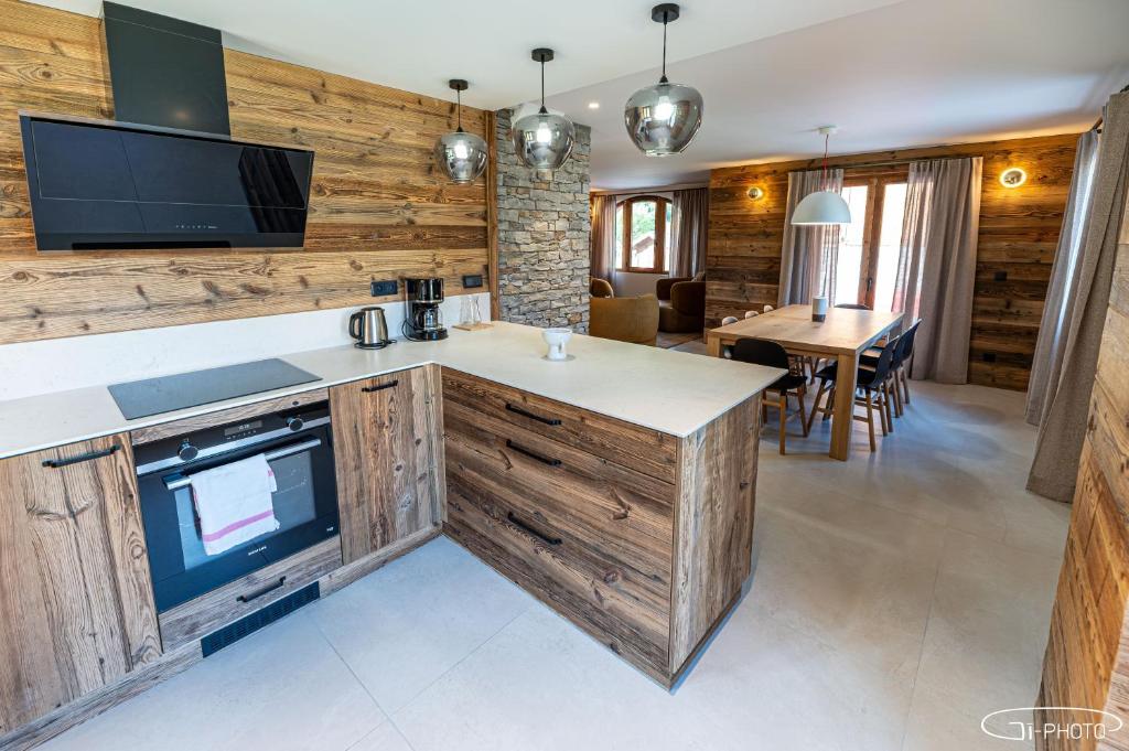 a kitchen with wooden cabinets and a tv in a room at Chalet Azureva Sauna, Jacuzzi, Spa in Levassaix