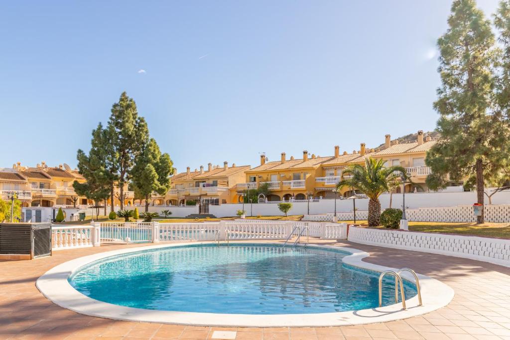 a swimming pool in a courtyard with houses in the background at Sol y Sombra in El Campello