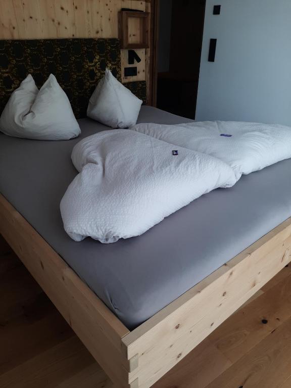 a bed with white blankets and pillows on it at Ladinser Hof Kuschelecke in Castelrotto