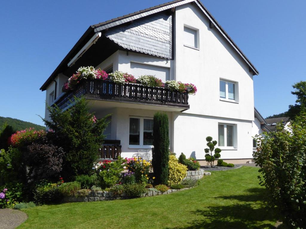 a white house with a balcony with flowers at Ferienwohnung Waltraud in Brilon