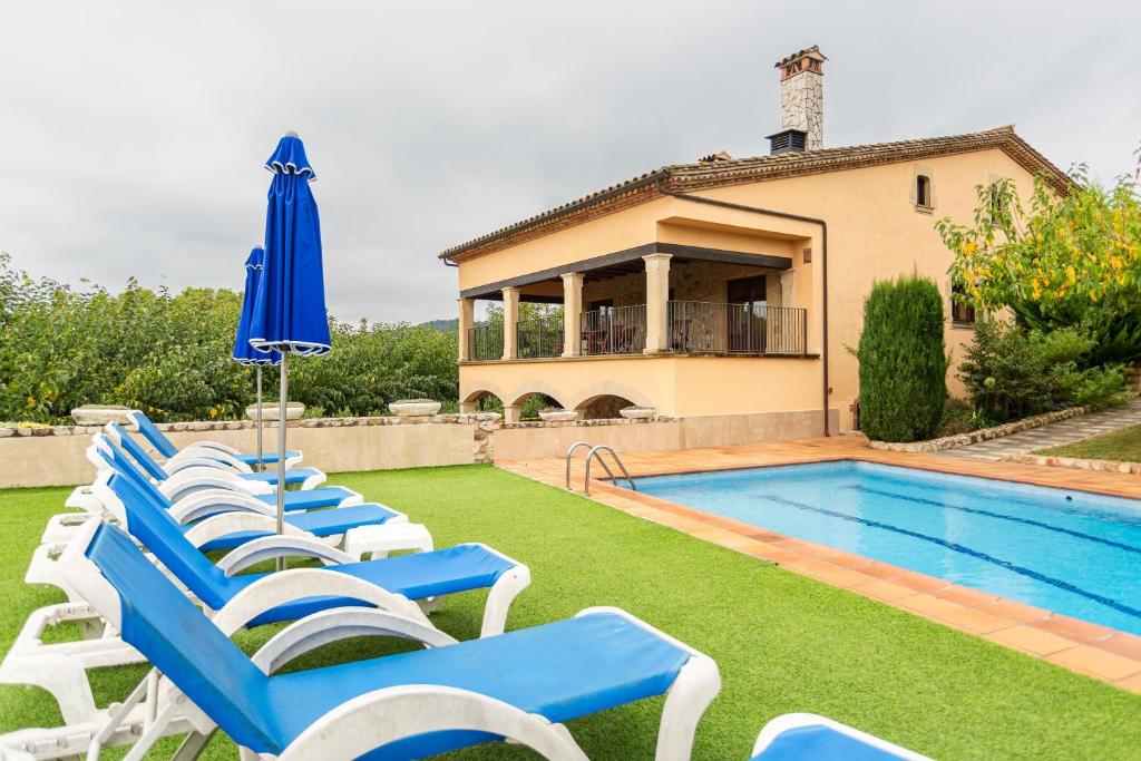 a group of blue and white chairs next to a swimming pool at Rural Mas Vila in Fogás de Tordera