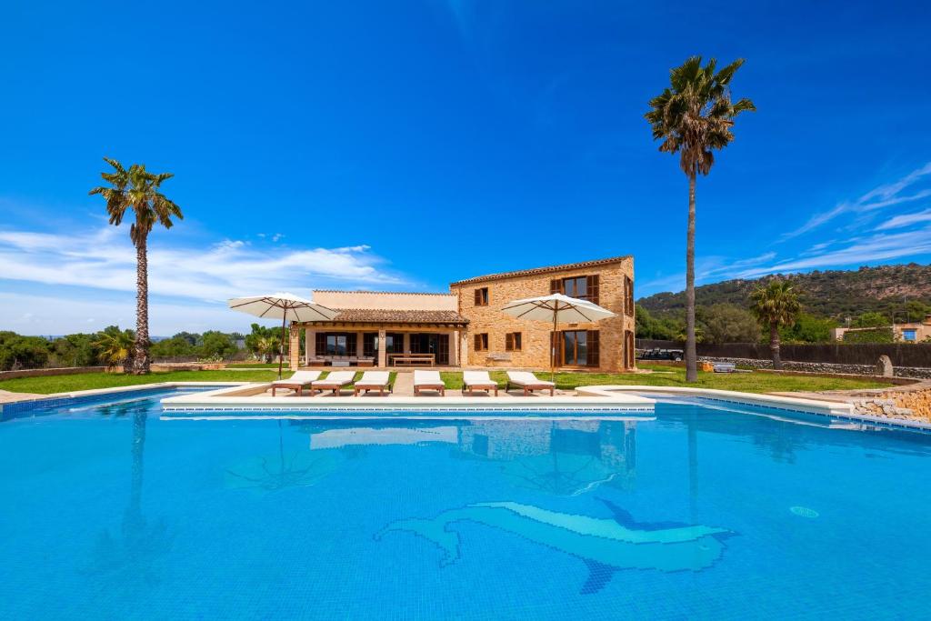 a swimming pool in front of a house with palm trees at Finca Mirador Capdepera in Capdepera