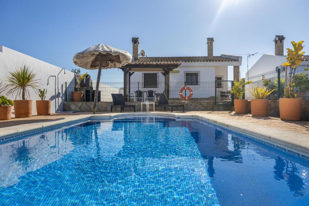a swimming pool with blue water in front of a house at Chalet El Cancelín in Conil de la Frontera