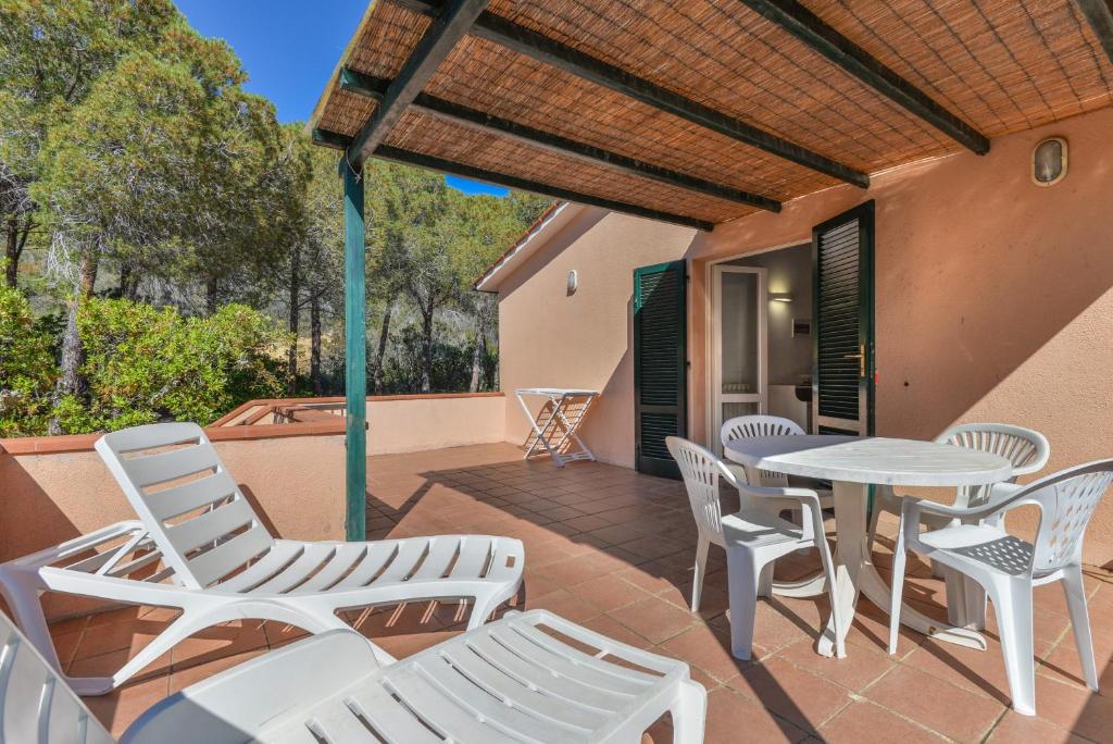 a patio with white chairs and a table and a table at Appartamento La Spiga in Procchio