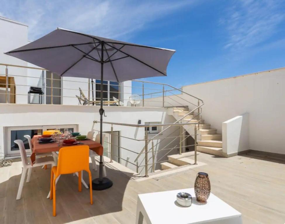 a patio with a table and an umbrella at Casa da Madou in Setúbal
