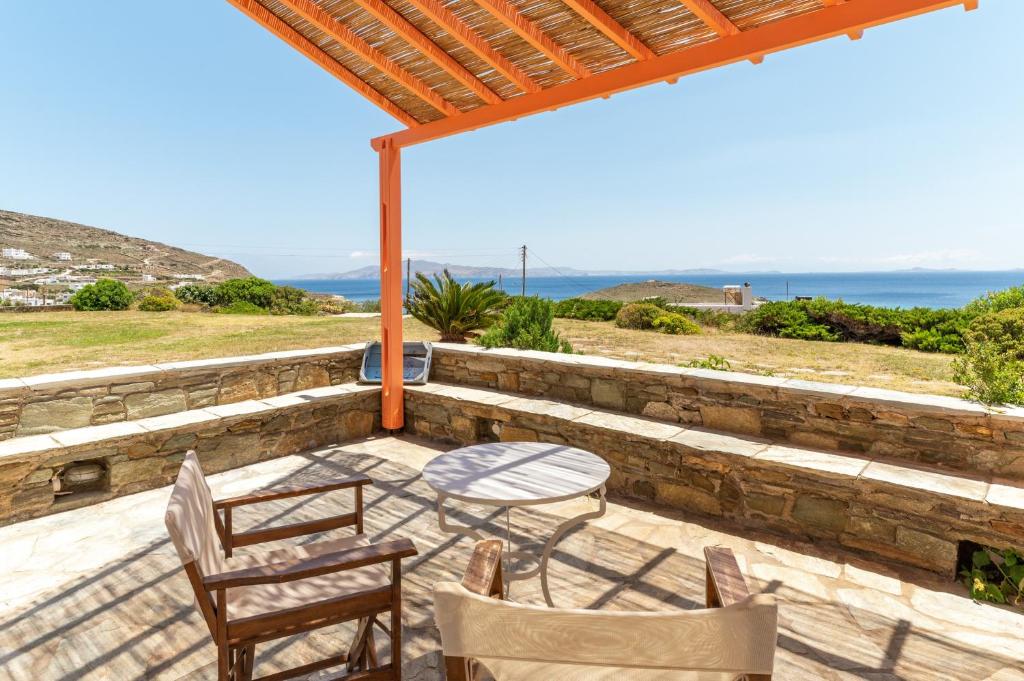 a patio with a table and chairs and the ocean at Anemologio 201 Tinos in Agios Ioannis