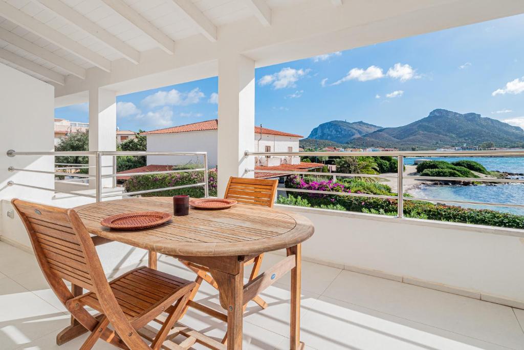 a table and chairs on a balcony with a view of the water at Villa Cormorani 1 in Golfo Aranci