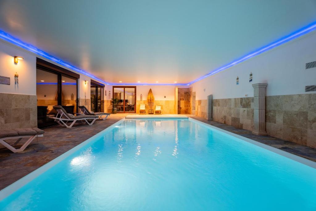 a swimming pool in a house with blue lighting at La Perle Bleue proche Strasbourg in Hoerdt