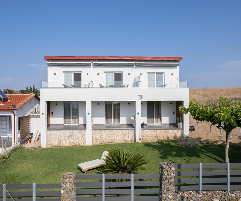 a white house with a fence in front of it at Sunset View House In Chalkidiki in Nea Potidaea
