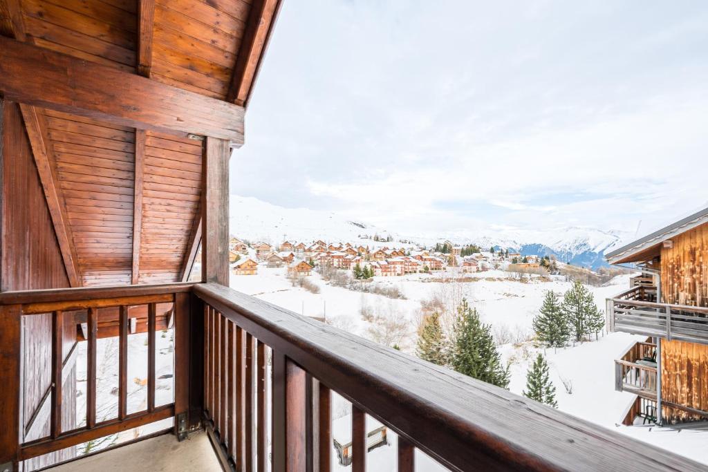 a balcony with a view of a town in the snow at Duplex confortable avec piscine in La Toussuire