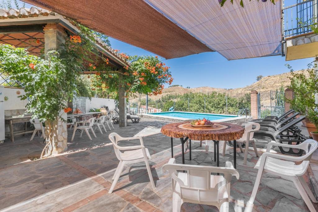 a patio with a table and chairs and a pool at Casa Roque in Monachil