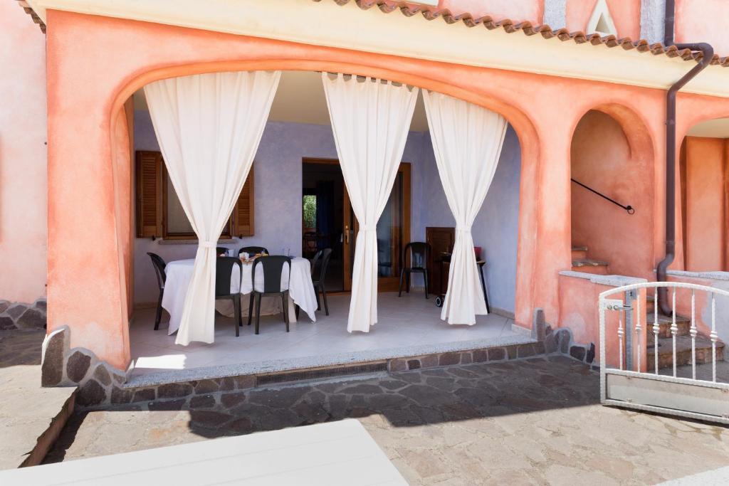 a dining room with white curtains and a table at Granito's in Monte Petrosu