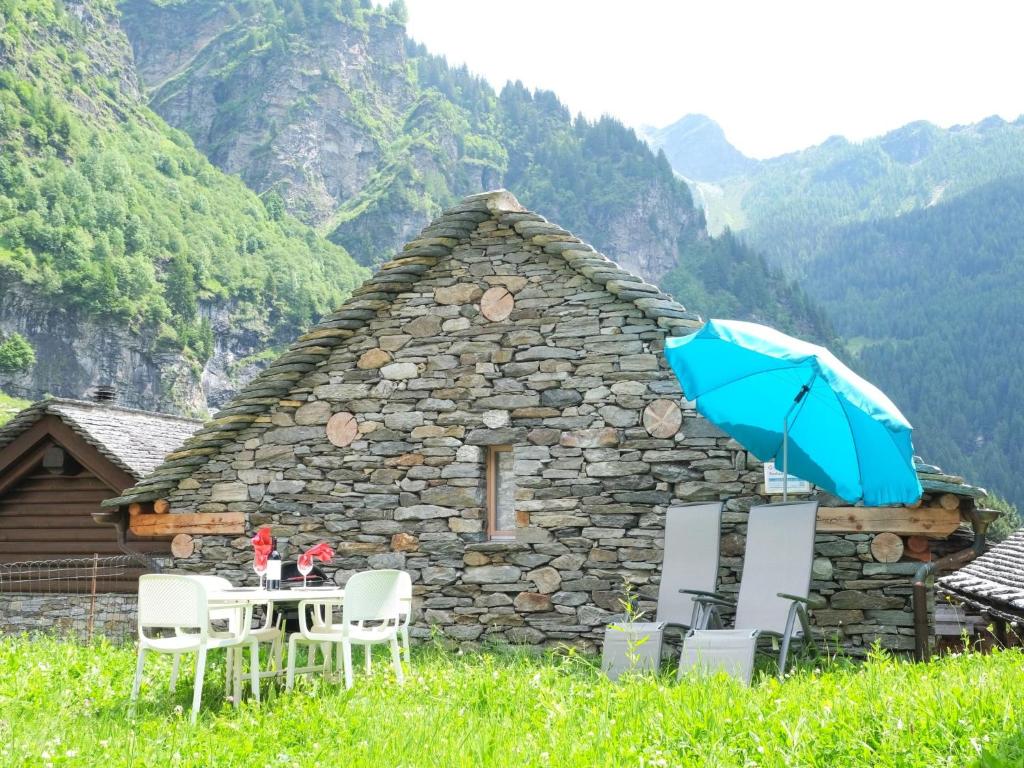 a table with chairs and an umbrella in front of a building at Holiday Home Rustico La Dimora by Interhome in Malvaglia