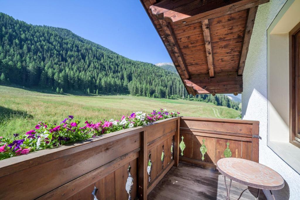 a balcony with flowers and a table and a view at Rieglhof Apartment Hennennest in Curon Venosta