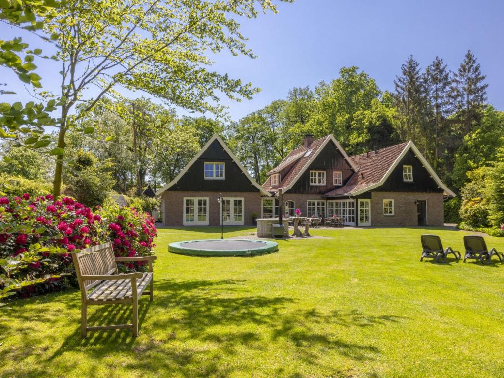 a house with a yard with chairs and flowers at Holiday Home Het Landhuis by Interhome in Losser