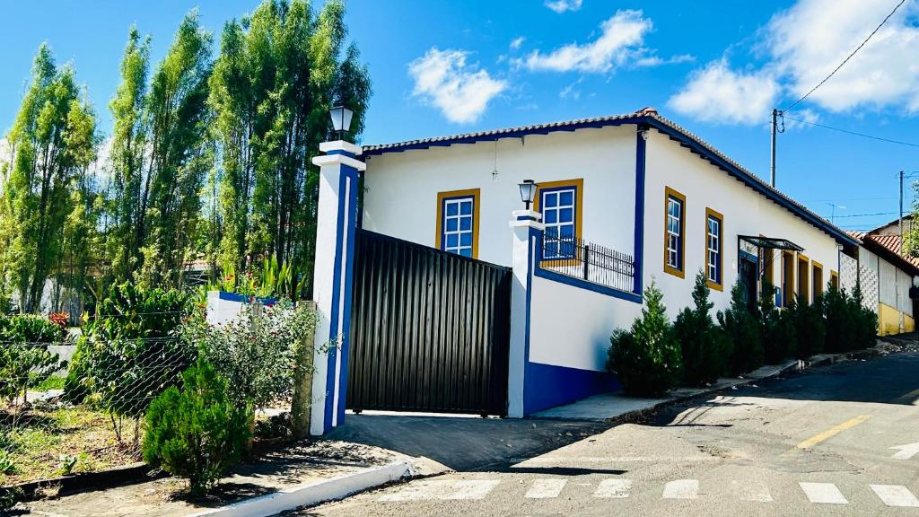 a white and blue house with a gate at Casa da Dóta no paraíso de Furnas e Capitólio in São José da Barra