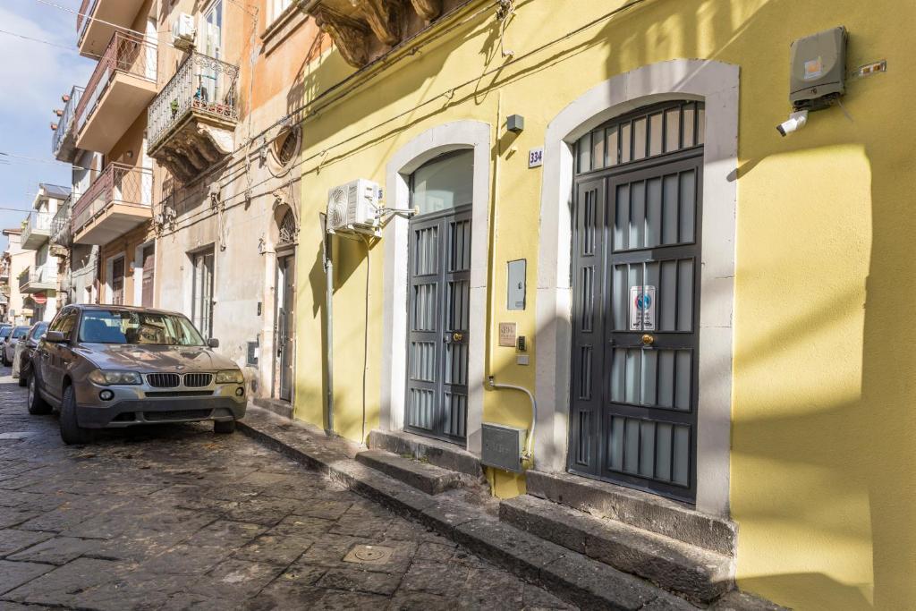 a car parked on a street next to a yellow building at Pm House in Misterbianco