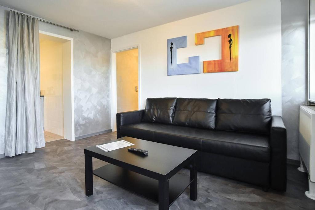 ein Wohnzimmer mit einem Ledersofa und einem Couchtisch in der Unterkunft Apartment Grey Stuttgart in Stuttgart