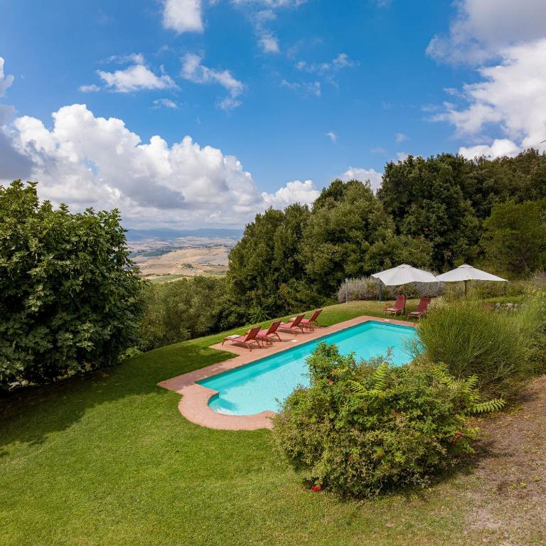a swimming pool in a yard with chairs and trees at Fattoria La Striscia in Gambassi Terme