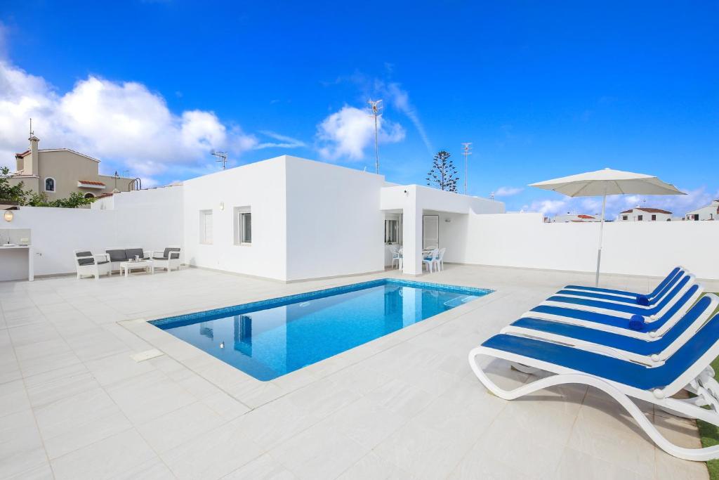 a swimming pool with two lounge chairs and an umbrella at Villa Aday and Ixeia in Cala Blanca