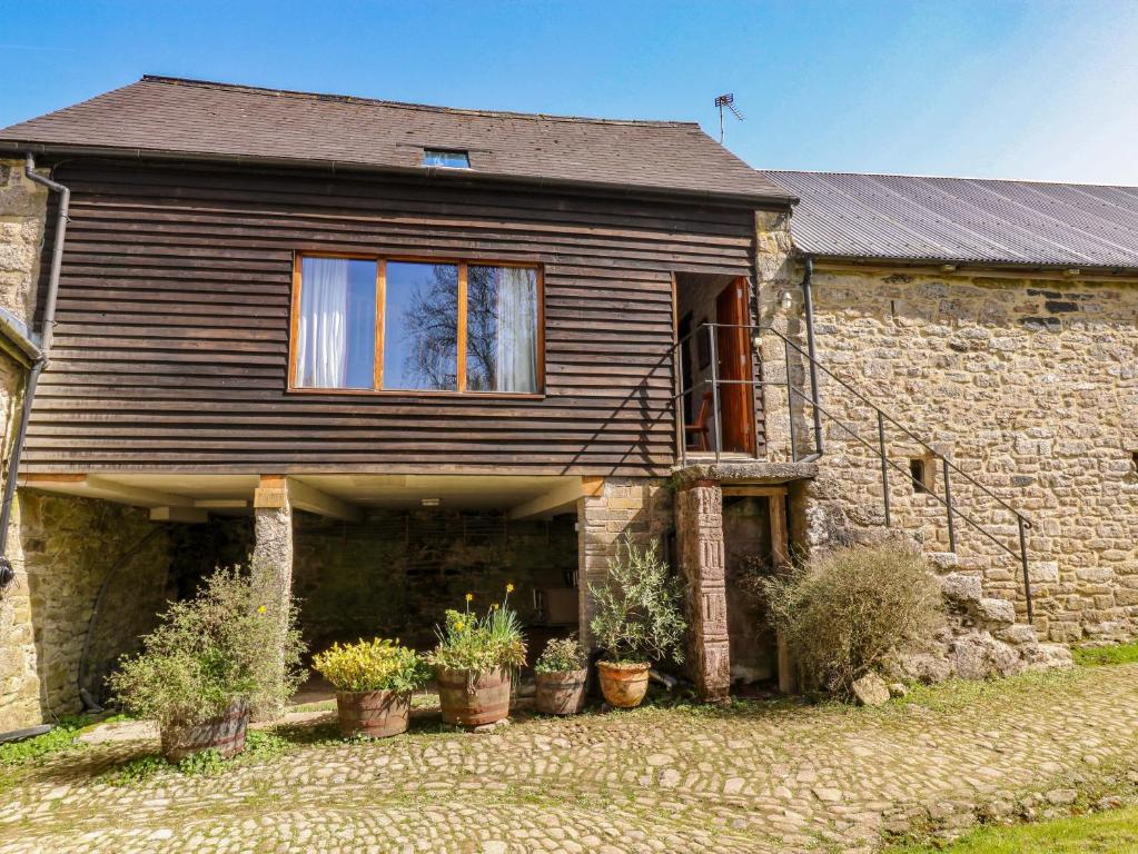 an old stone house with potted plants in front of it at Swallows Nest in Newton Abbot