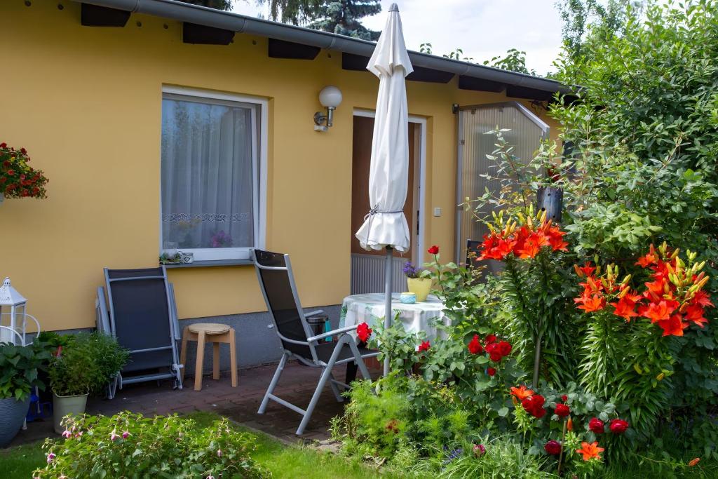 a yellow house with a table and an umbrella and flowers at Ferienhaus Stahlberg in Potsdam
