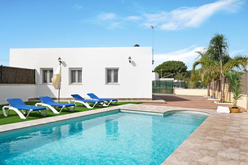 a swimming pool with blue chairs and a house at Villa Montemedio - Paco in El Soto