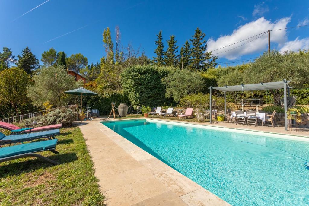 a swimming pool in a yard with chairs and tables at Gîte Les Tarentes avec piscine in Cotignac