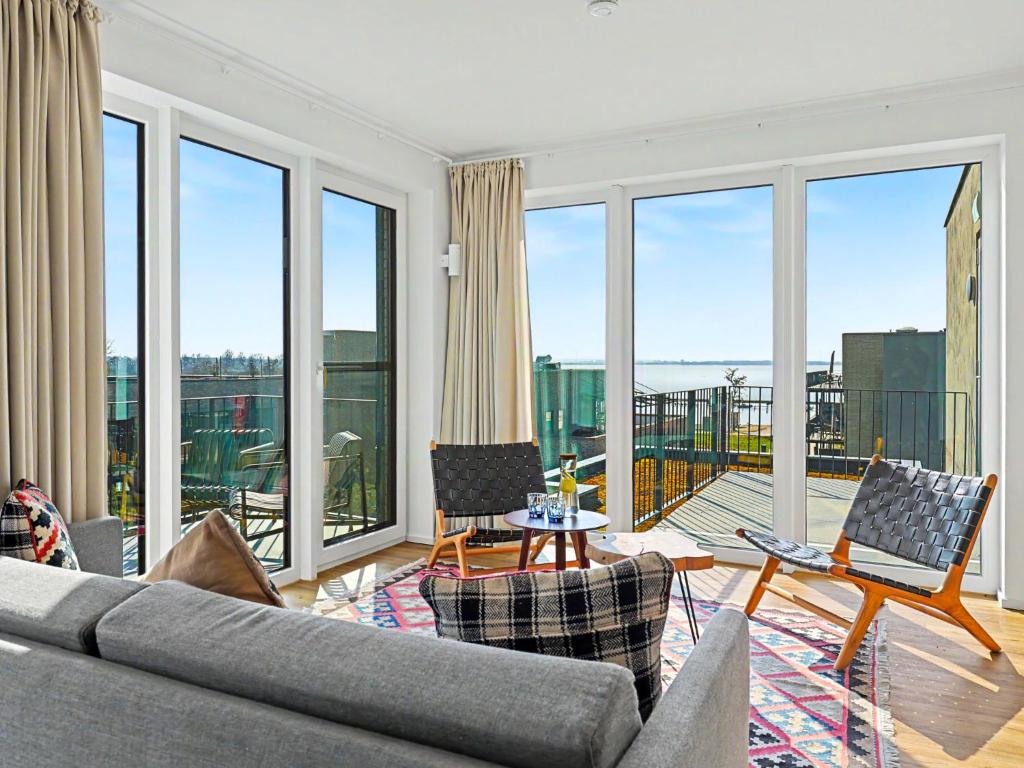 a living room with a couch and chairs and windows at Apartment Penthouse Imort - 654 by Interhome in Lembruch